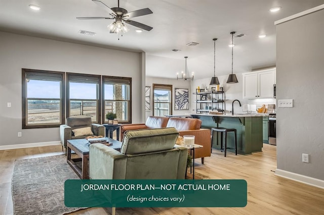 living room with ceiling fan with notable chandelier, sink, and light hardwood / wood-style flooring