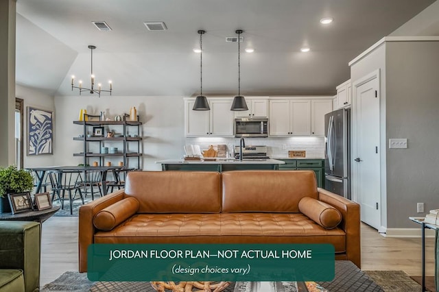 living room featuring an inviting chandelier, light wood-type flooring, sink, and vaulted ceiling