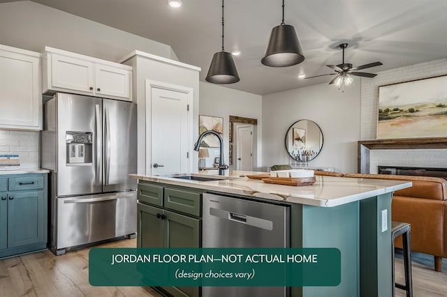 kitchen featuring a kitchen island with sink, white cabinets, ceiling fan, appliances with stainless steel finishes, and decorative light fixtures