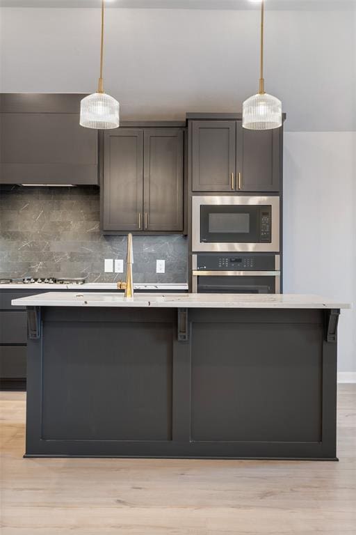 kitchen featuring built in microwave, stainless steel oven, decorative light fixtures, and a center island