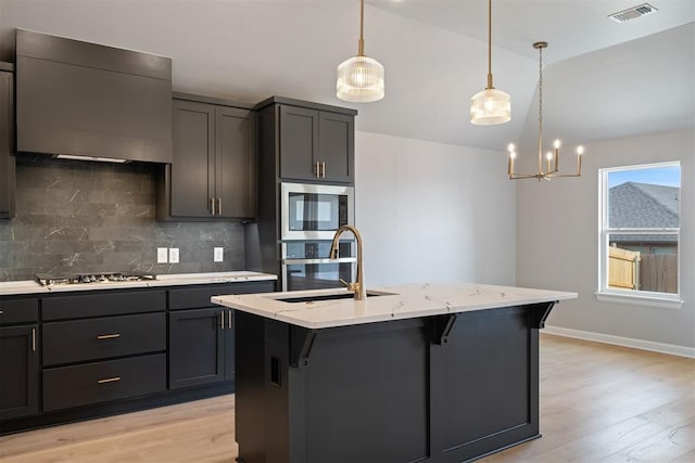 kitchen featuring stainless steel appliances, an island with sink, and wall chimney exhaust hood