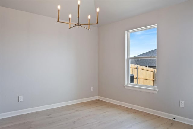 unfurnished room featuring a notable chandelier and light hardwood / wood-style flooring