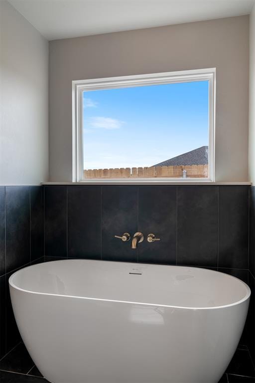 bathroom with a bathing tub, plenty of natural light, and tile walls