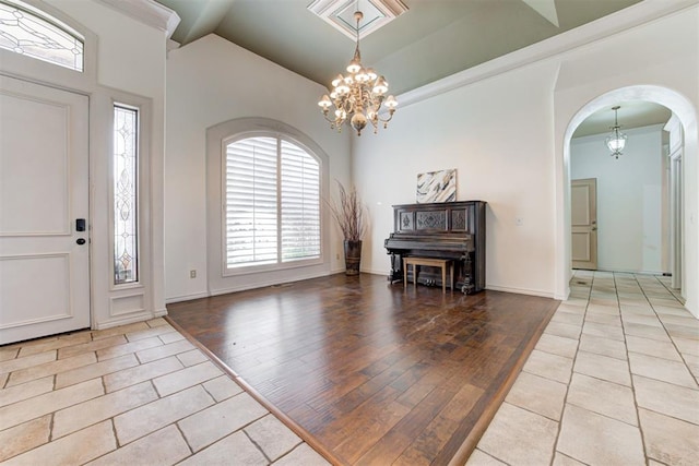 foyer with light hardwood / wood-style flooring, high vaulted ceiling, ornamental molding, and a notable chandelier