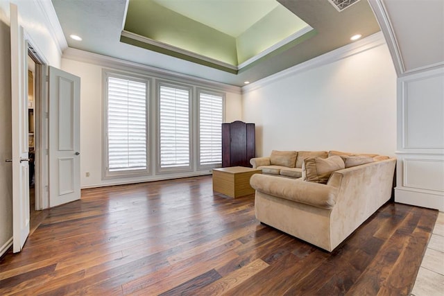 living room featuring dark hardwood / wood-style floors, crown molding, and a tray ceiling