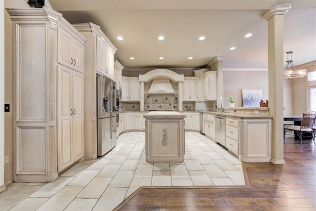 kitchen featuring light hardwood / wood-style flooring, appliances with stainless steel finishes, a kitchen island, custom exhaust hood, and ornamental molding