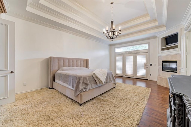 bedroom with a tile fireplace, dark hardwood / wood-style flooring, a raised ceiling, and ornamental molding