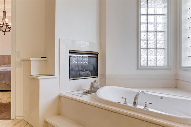 bathroom with a chandelier and a washtub