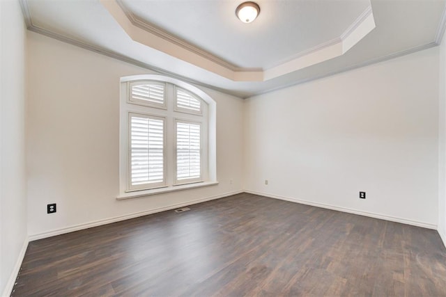 spare room with a raised ceiling, dark hardwood / wood-style flooring, and ornamental molding