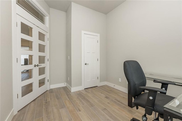 home office with french doors and light hardwood / wood-style floors