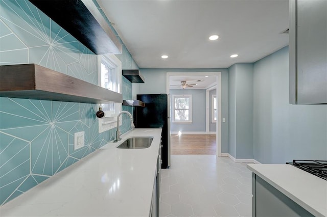 kitchen with black refrigerator, sink, tile walls, and light hardwood / wood-style flooring