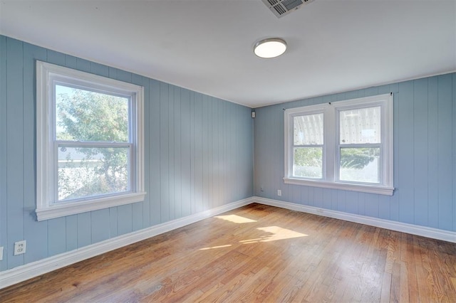 spare room with wooden walls and light hardwood / wood-style flooring