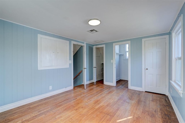 unfurnished bedroom featuring light hardwood / wood-style floors and wooden walls