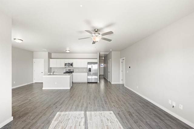 kitchen featuring white cabinetry, sink, dark wood-type flooring, stainless steel appliances, and a kitchen island with sink