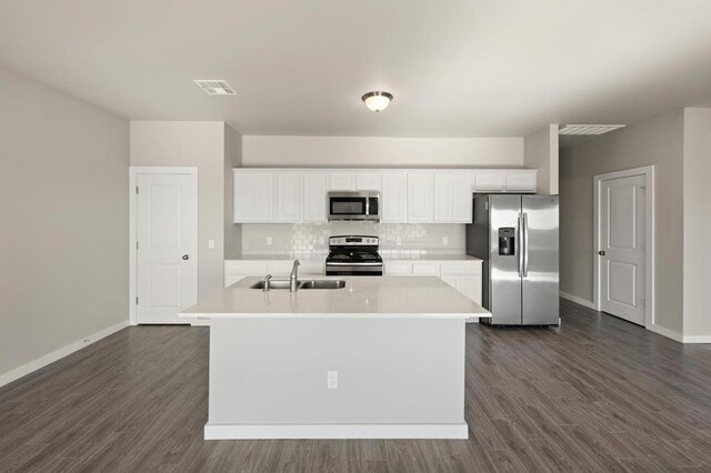 kitchen with backsplash, a kitchen island with sink, dark hardwood / wood-style flooring, white cabinetry, and stainless steel appliances