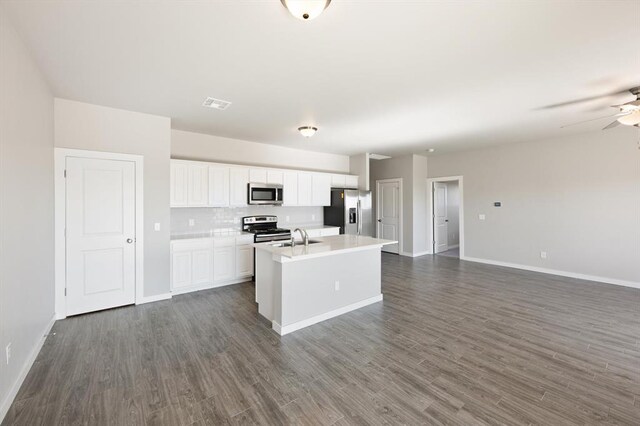 kitchen with stainless steel appliances, a kitchen island with sink, dark wood-type flooring, sink, and white cabinets