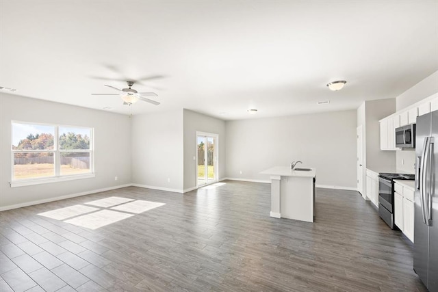 kitchen with a wealth of natural light, white cabinetry, a kitchen island with sink, and appliances with stainless steel finishes