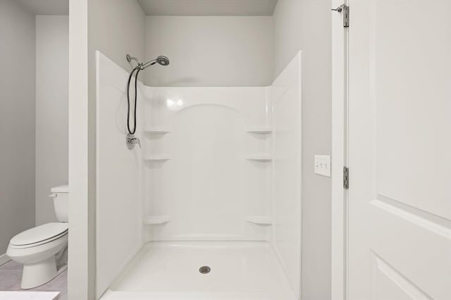 bathroom with a shower, tile patterned floors, and toilet