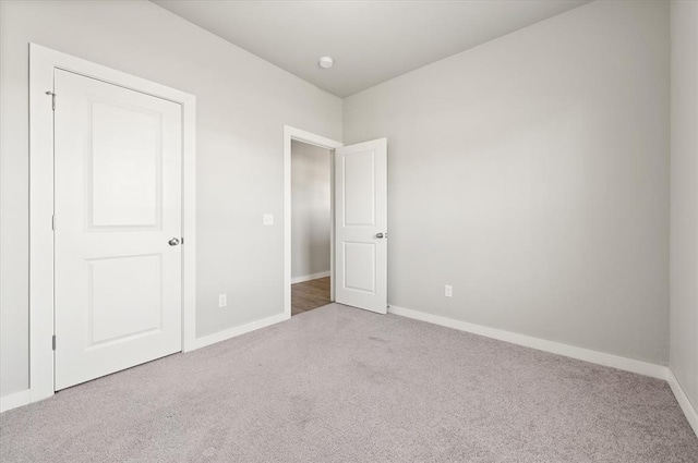 unfurnished bedroom featuring light colored carpet and a closet