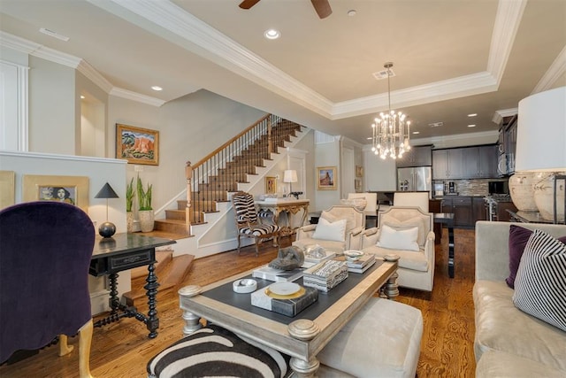 living room featuring ceiling fan with notable chandelier, dark hardwood / wood-style flooring, a raised ceiling, and crown molding