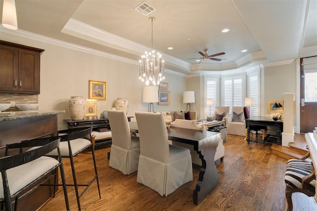 dining room with a tray ceiling, crown molding, ceiling fan, and dark hardwood / wood-style floors