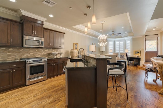 kitchen with light hardwood / wood-style floors, sink, stainless steel appliances, and hanging light fixtures