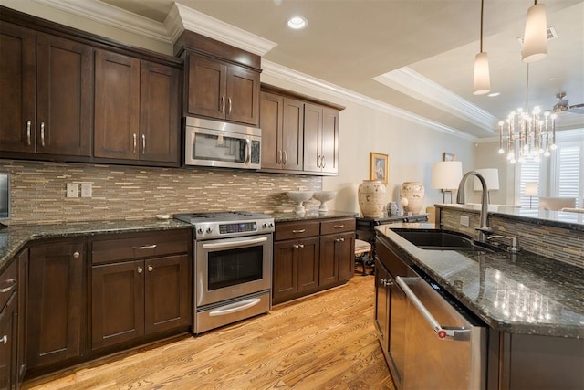 kitchen featuring pendant lighting, sink, dark stone countertops, light wood-type flooring, and stainless steel appliances