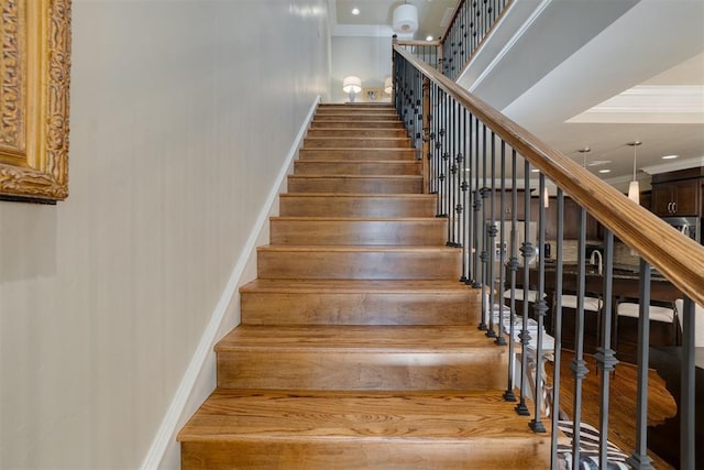 staircase with wood-type flooring and ornamental molding