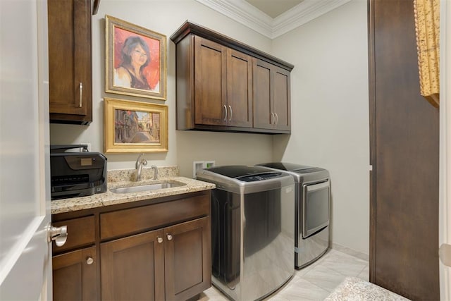 laundry area featuring washer and clothes dryer, crown molding, cabinets, and sink