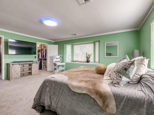 carpeted bedroom with a spacious closet, crown molding, and a closet