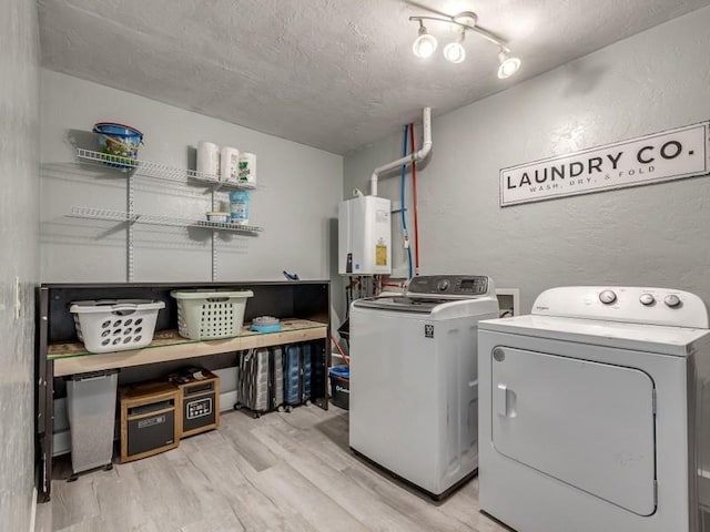 washroom featuring washer and clothes dryer, tankless water heater, light wood-type flooring, and a textured ceiling