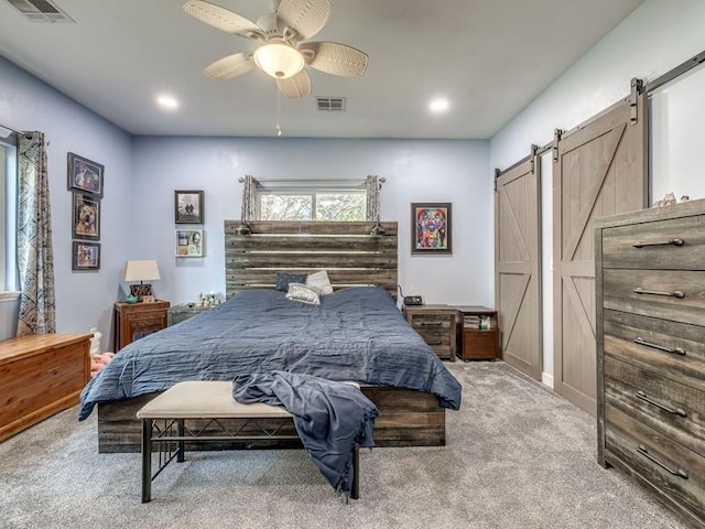 bedroom featuring ceiling fan, a barn door, and light colored carpet