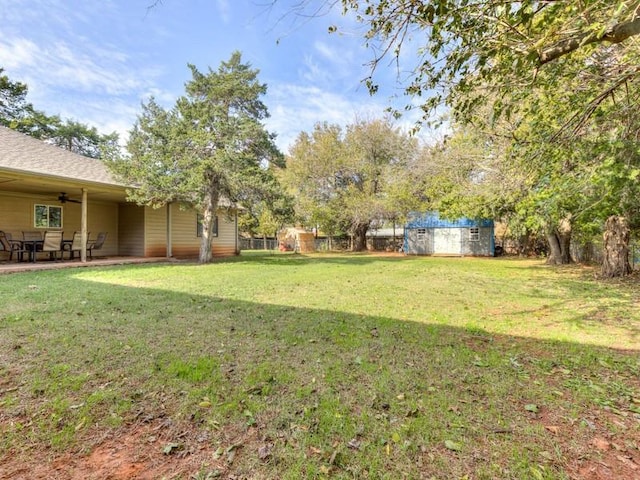 view of yard featuring ceiling fan and a storage shed