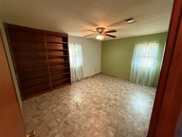 unfurnished bedroom with ceiling fan and a textured ceiling