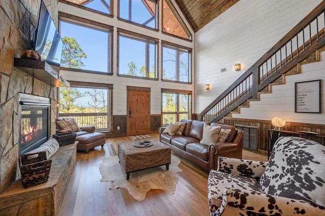 living room featuring high vaulted ceiling, wooden walls, a fireplace, wood ceiling, and hardwood / wood-style flooring