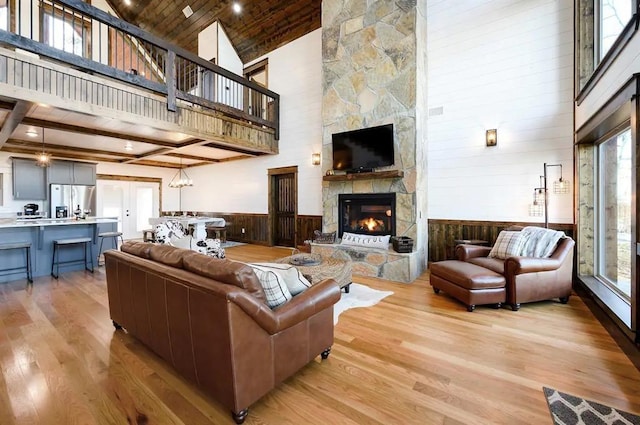 living room with a fireplace, high vaulted ceiling, a healthy amount of sunlight, and light wood-type flooring