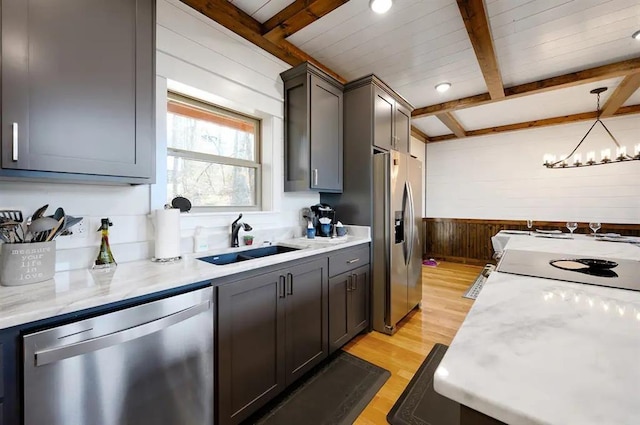 kitchen with pendant lighting, sink, appliances with stainless steel finishes, beamed ceiling, and light hardwood / wood-style floors