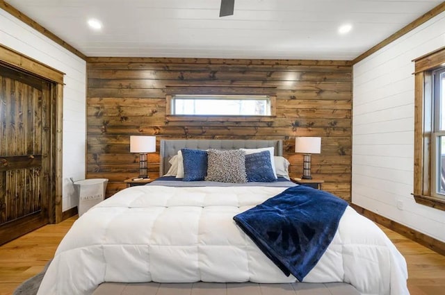 bedroom with wood walls, light hardwood / wood-style flooring, and ceiling fan