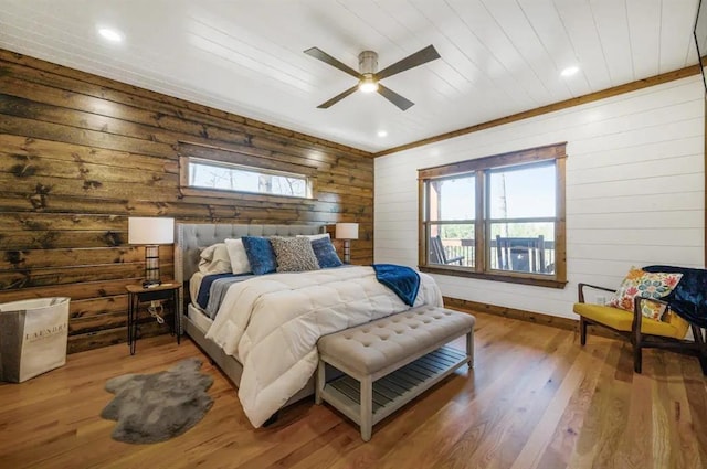 bedroom featuring hardwood / wood-style floors, ceiling fan, and wood walls