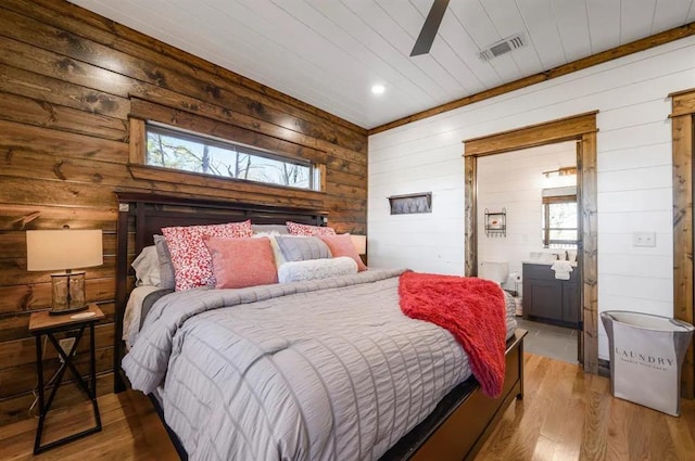 bedroom with hardwood / wood-style floors, multiple windows, wooden walls, and ceiling fan