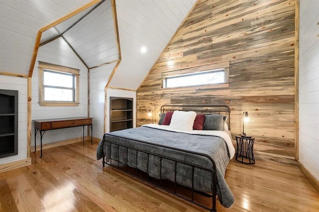 bedroom featuring wood ceiling, light hardwood / wood-style floors, lofted ceiling, and wooden walls