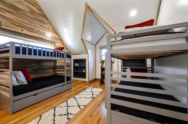 bedroom with hardwood / wood-style flooring, wood walls, and lofted ceiling