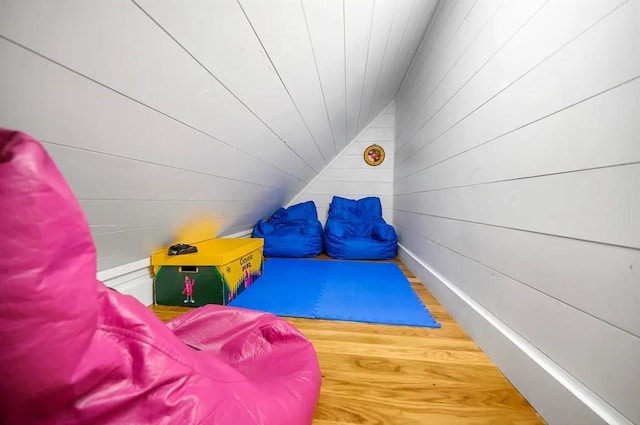 game room with wood-type flooring, wooden walls, and lofted ceiling