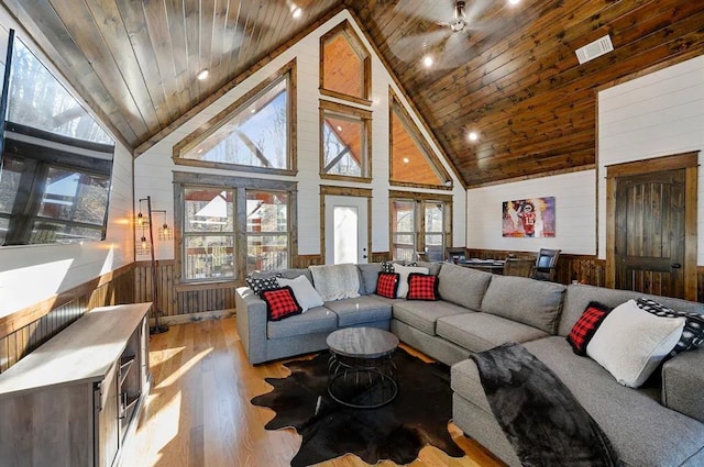 living room featuring wooden ceiling, high vaulted ceiling, wooden walls, light hardwood / wood-style flooring, and ceiling fan