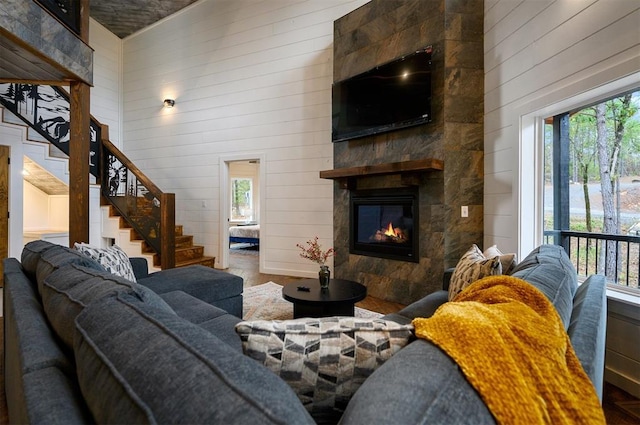 living room with a wealth of natural light, a fireplace, high vaulted ceiling, and wood walls