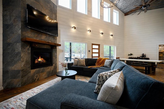 living room with wood ceiling, ceiling fan, hardwood / wood-style flooring, high vaulted ceiling, and a tiled fireplace