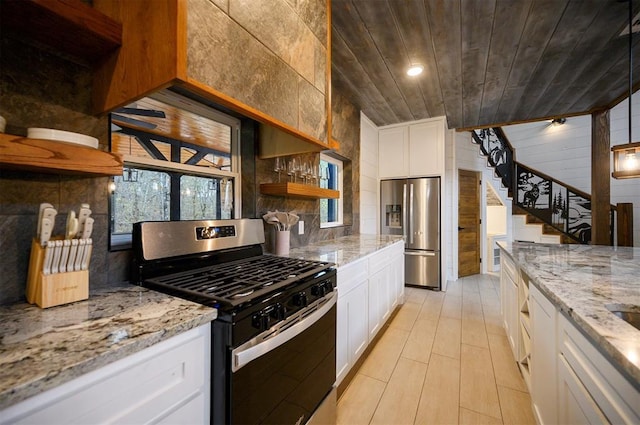 kitchen featuring white cabinetry, stainless steel appliances, light stone counters, wooden walls, and wood ceiling