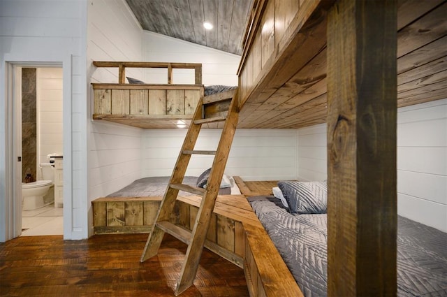 mudroom featuring dark hardwood / wood-style floors, wood walls, and vaulted ceiling