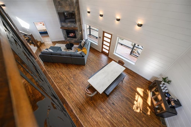 living room featuring dark hardwood / wood-style flooring, a stone fireplace, and lofted ceiling