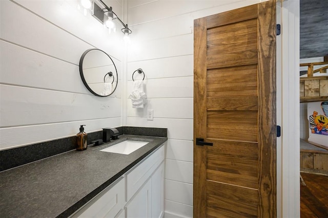 bathroom with hardwood / wood-style floors, vanity, and wooden walls